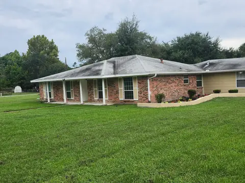 Graceful Meadows Assisted Living, a single-story brick home with a wide green lawn in Tomball, TX