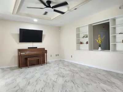 Common room with a piano, wall-mounted TV, and built-in shelves